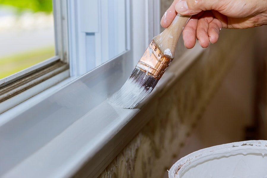 a worker painting a upvc window with white paint
